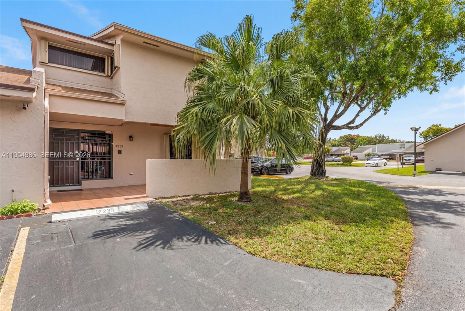 A two-story tan townhouse features a palm tree, a paved driveway, and a gated entrance — 12233 SW 24th Ter # 35, Miami FL 33175, MIAMI, FL