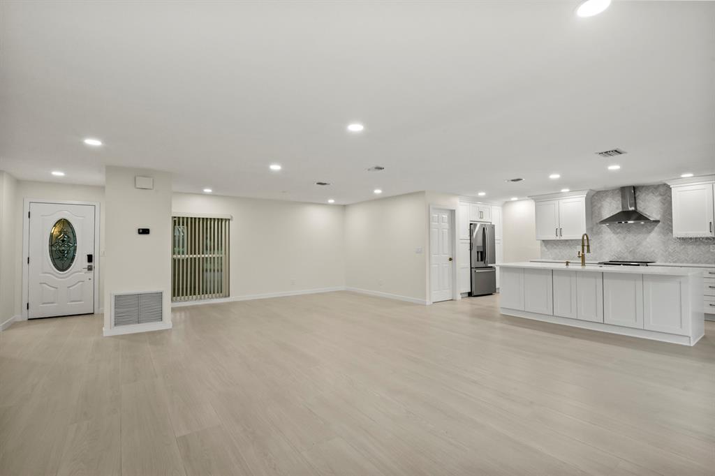 An open-concept living area features light wood flooring, a white kitchen island, and white cabinetry — 2703 LANCASTER DRIVE, SUN CITY CENTER, FL