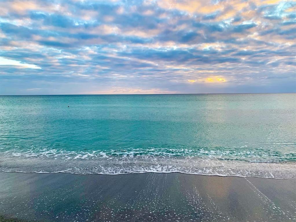 A view of turquoise ocean waves washing onto a dark sandy beach under a cloudy sky — 561 GULF BAY ROAD, LONGBOAT KEY, FL