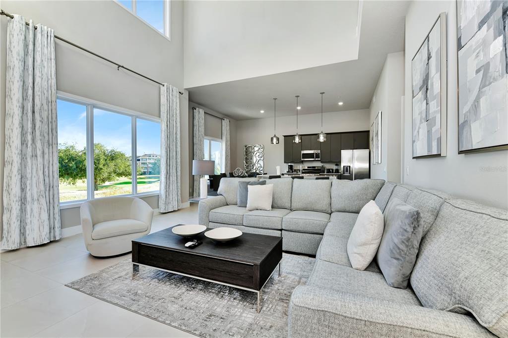 A modern living room with a sectional sofa, coffee table, and an open kitchen beyond — 7740 SANDY RIDGE DRIVE UNIT 231, KISSIMMEE, FL