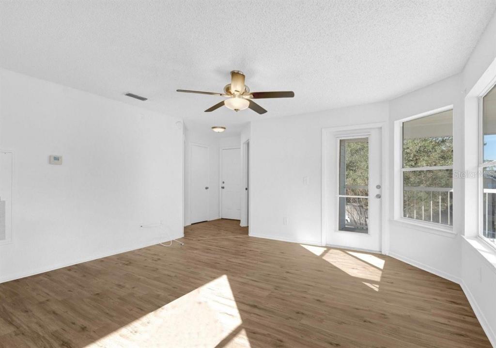 An empty room with light wood-look flooring, white walls, a ceiling fan, and a glass door — 2585 GRASSY POINT DRIVE UNIT 211, LAKE MARY, FL