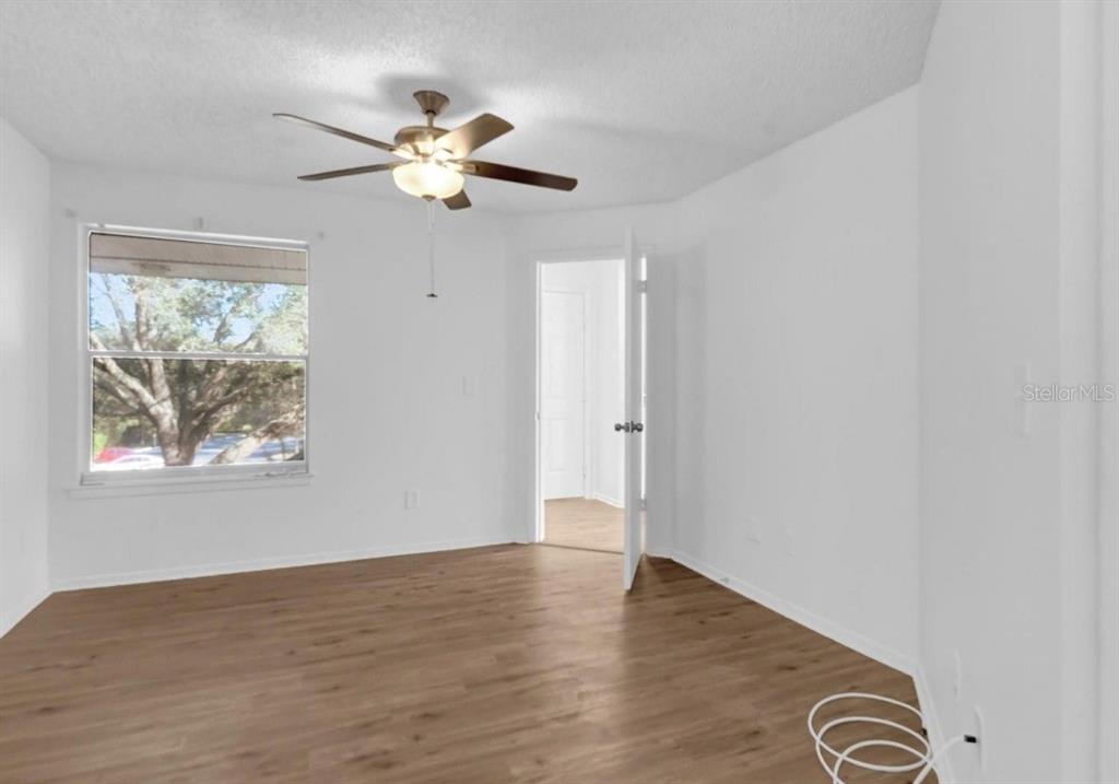 An empty bedroom features white walls, wood-look flooring, a ceiling fan, and a window — 2585 GRASSY POINT DRIVE UNIT 211, LAKE MARY, FL