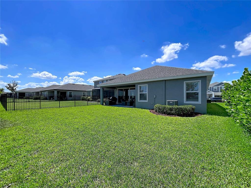 The exterior of a gray house features a covered patio and a fenced backyard — 6290 ROADSTEAD COURT, APOLLO BEACH, FL