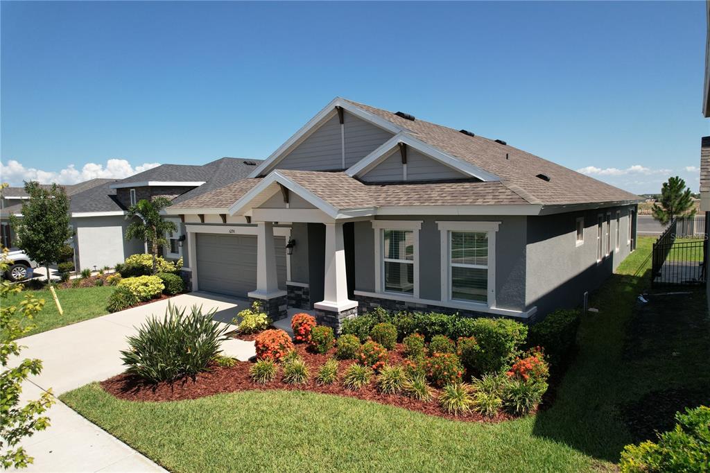 A single-story house with a gray stucco exterior, stone accents, and a two-car garage — 6290 ROADSTEAD COURT, APOLLO BEACH, FL