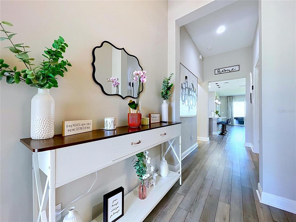 A white console table sits in a hallway with wood-look flooring and a decorative mirror — 6290 ROADSTEAD COURT, APOLLO BEACH, FL