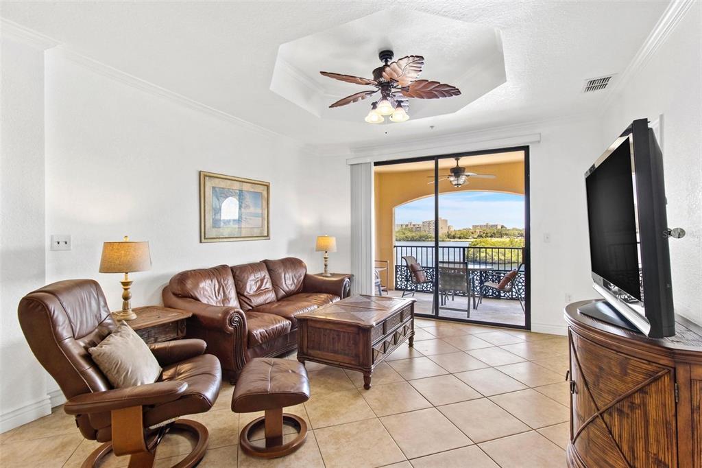 A living room with leather furniture, a tray ceiling, and a balcony overlooking the water — 2739 VIA CAPRI UNIT 1039, CLEARWATER, FL