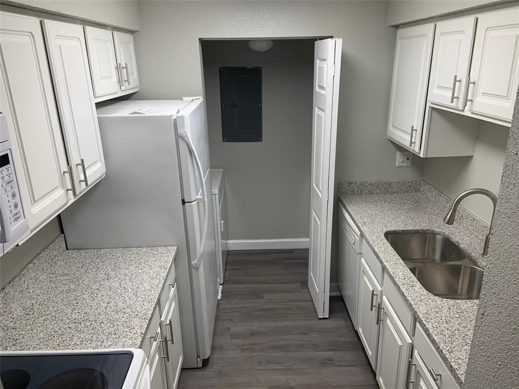 A galley kitchen features white cabinets, granite-look countertops, stainless steel sink, and a laundry closet — 3756 IDLEBROOK CIRCLE UNIT 204, CASSELBERRY, FL