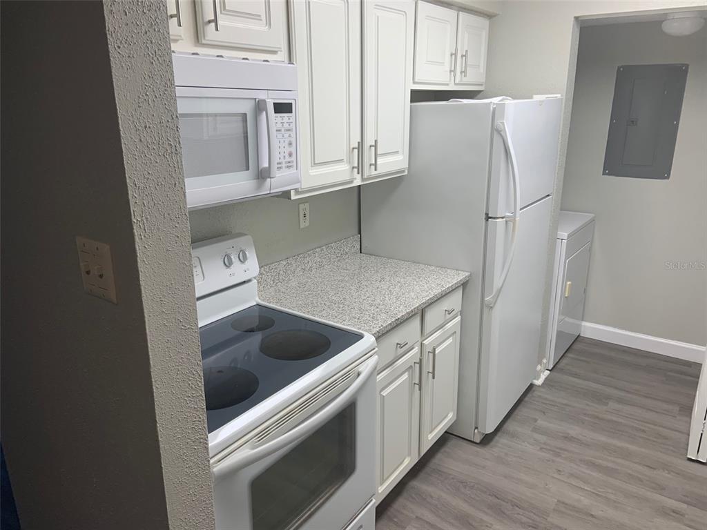 A kitchen features white cabinets, a white stove, a microwave, and a white refrigerator — 3756 IDLEBROOK CIRCLE UNIT 204, CASSELBERRY, FL