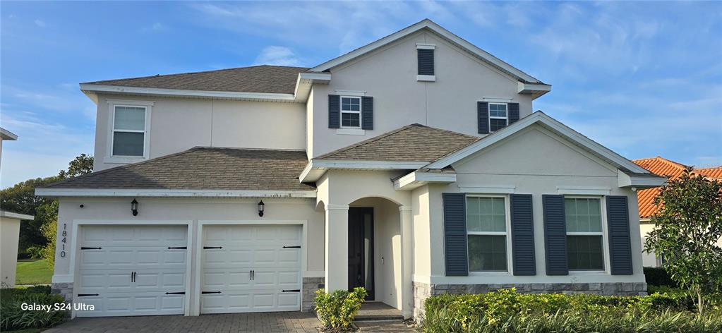 A two-story suburban house with a two-car garage, light-colored stucco, and dark shutters — 18410 BLUE HERON CIRCLE, DEER ISLAND, FL