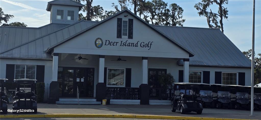 The exterior of the Deer Island Golf clubhouse features a metal roof and golf carts — 18410 BLUE HERON CIRCLE, DEER ISLAND, FL