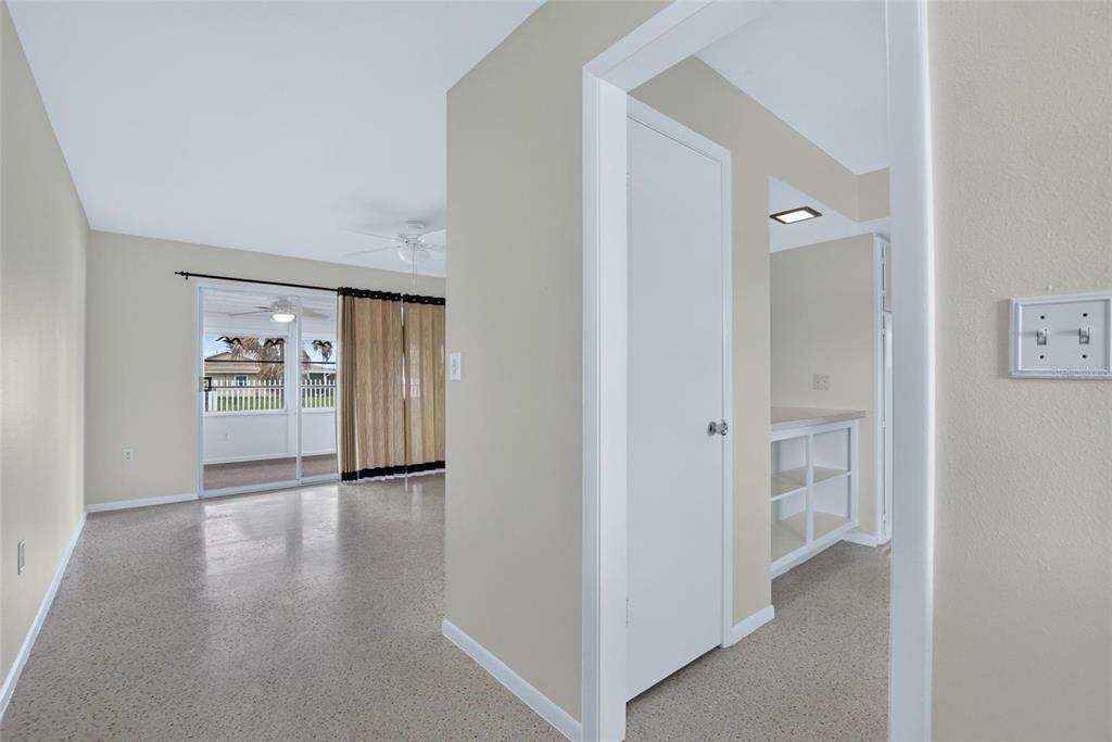 A view from a hallway into a living room with sliding glass doors and terrazzo flooring — 705 THUNDERBIRD AVENUE, SUN CITY CENTER, FL