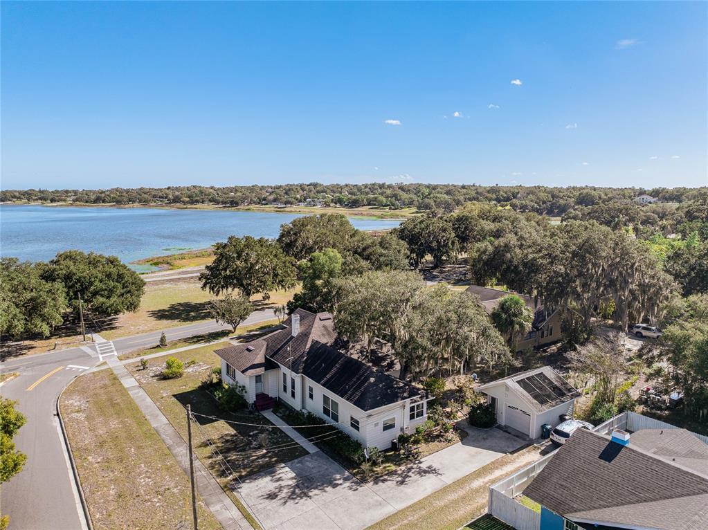 An aerial view shows a white house with a dark roof near a large lake — 102 S LAKESHORE BOULEVARD, LAKE WALES, FL