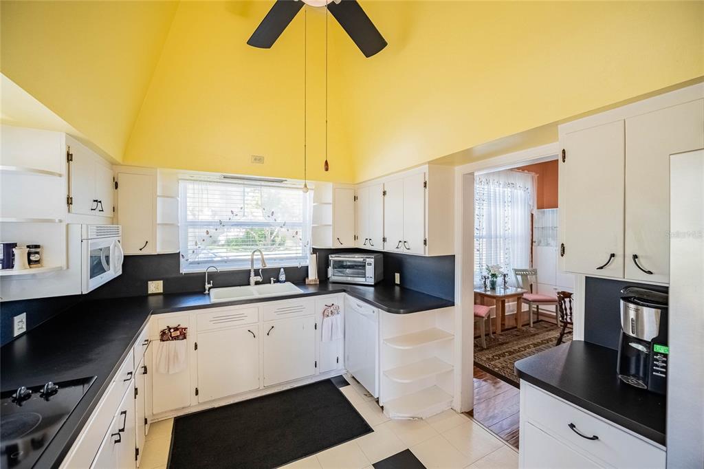 A kitchen with white cabinets, black countertops, yellow vaulted ceilings, and a ceiling fan — 102 S LAKESHORE BOULEVARD, LAKE WALES, FL