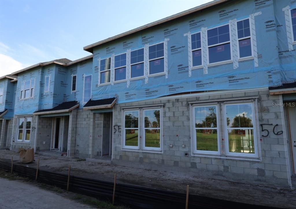 An exterior view of a multi-unit townhouse construction site with concrete block walls and housewrap — 3542 CASPIAN CHERVIL STREET, WESLEY CHAPEL, FL