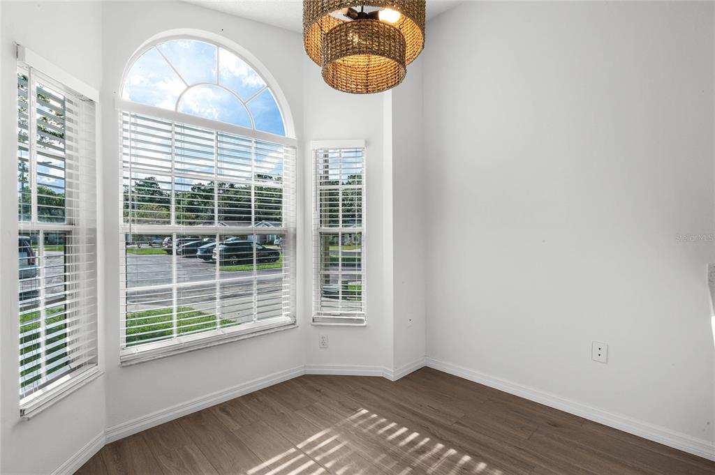 A bright dining nook features wood-look flooring, white walls, and a large arched window — 239 PANORAMA DRIVE, WINTER SPRINGS, FL