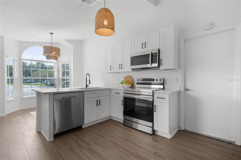 A kitchen with white cabinets, stainless steel appliances, and a peninsula island with a sink — 239 PANORAMA DRIVE, WINTER SPRINGS, FL