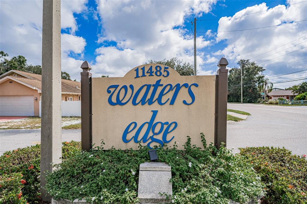 A sign for a residential community stands in front of a house and a road — 11485 OAKHURST ROAD UNIT 200-306, LARGO, FL