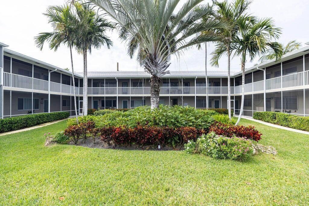 A two-story apartment complex surrounds a central courtyard with palm trees and landscaped garden beds — 426 NE 7th Avenue # 2b, Delray Beach FL 33483, DELRAY BEACH, FL