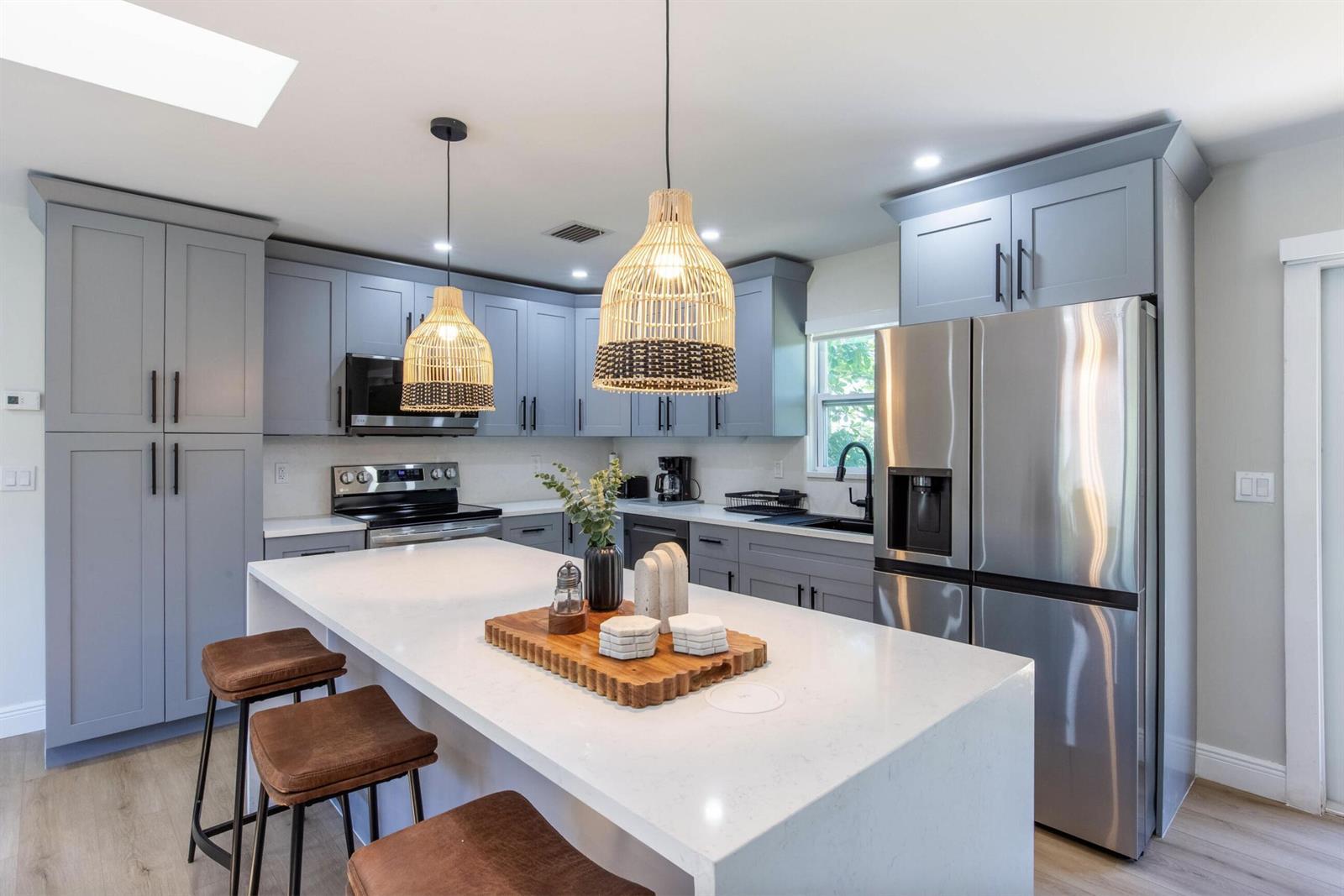 A kitchen features gray shaker cabinets, a white quartz island, and two woven pendant lights — 16932 W Aintree Drive W, FL 33470, FL