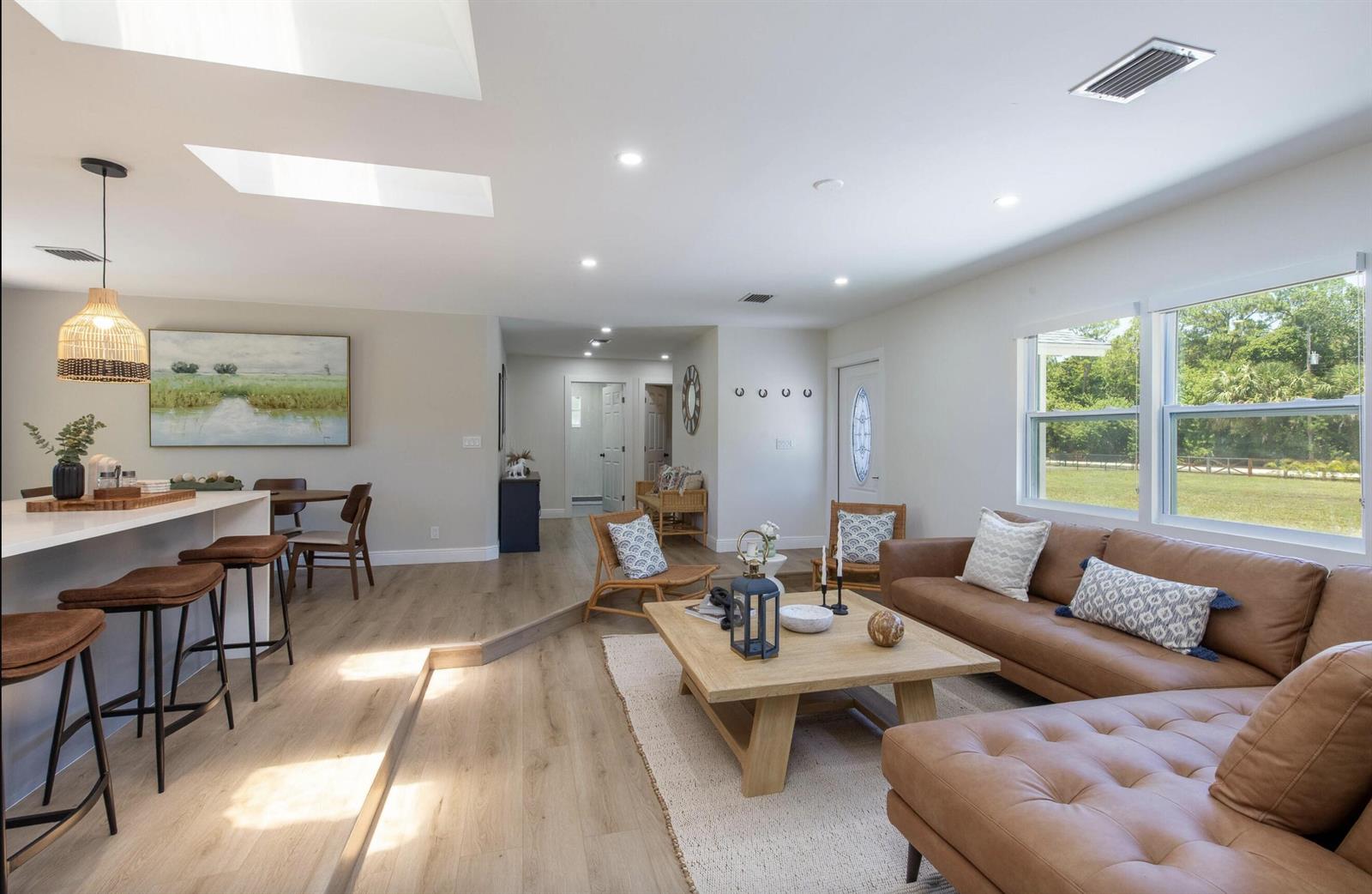 An open-concept living room and kitchen feature light wood flooring, a leather sectional, and skylights — 16932 W Aintree Drive W, FL 33470, FL