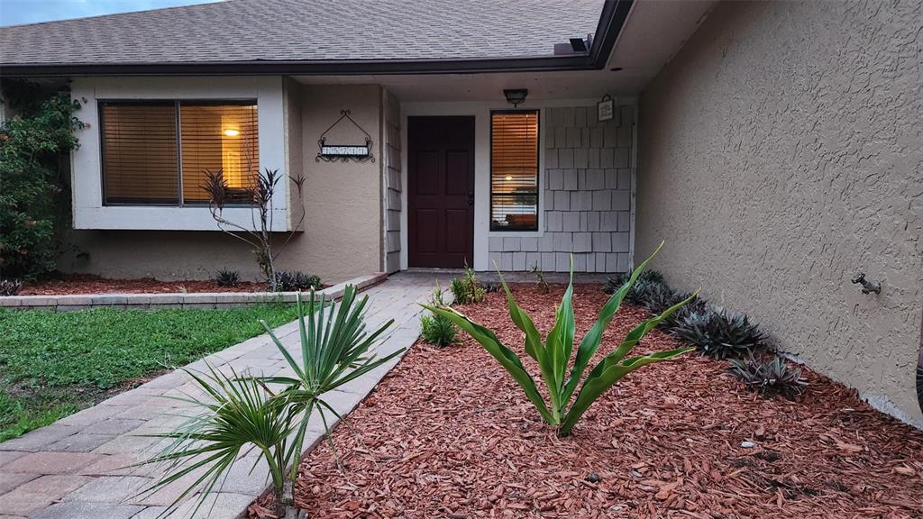 A front exterior view of a house with a paver walkway and mulched landscaping — 15711 SCRIMSHAW DRIVE, TAMPA, FL