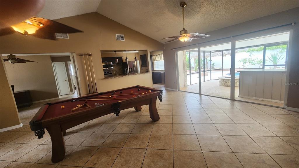 A game room features a pool table, tile flooring, and sliding glass doors to a patio — 15711 SCRIMSHAW DRIVE, TAMPA, FL