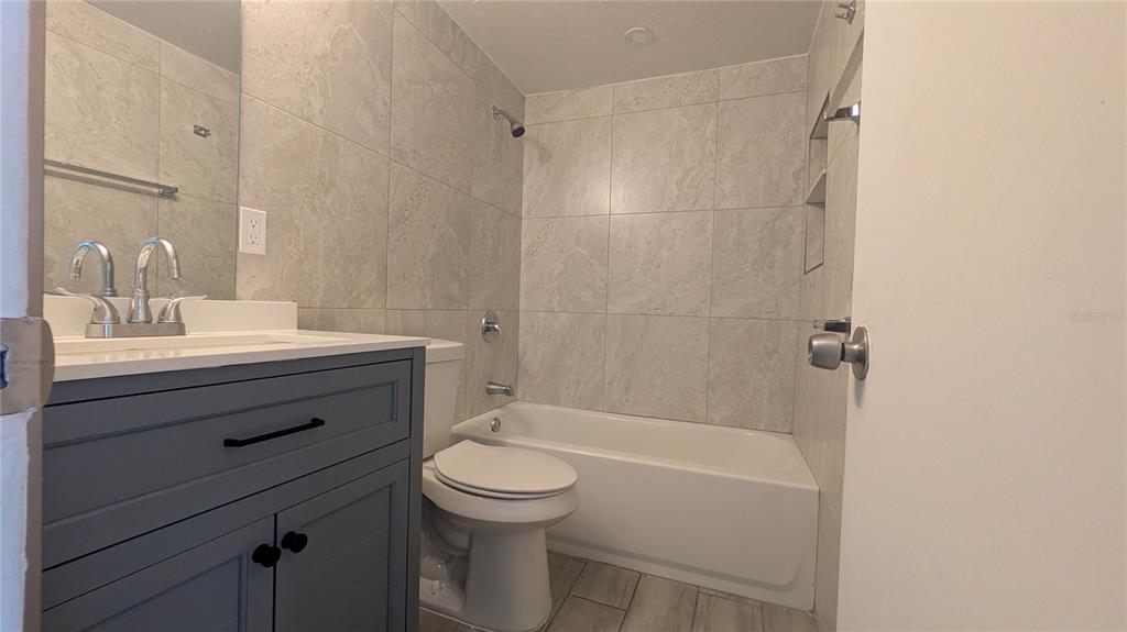 A bathroom features a gray vanity, a white toilet, and a tiled shower-tub combination — 5723 9TH STREET CIRCLE E, BRADENTON, FL