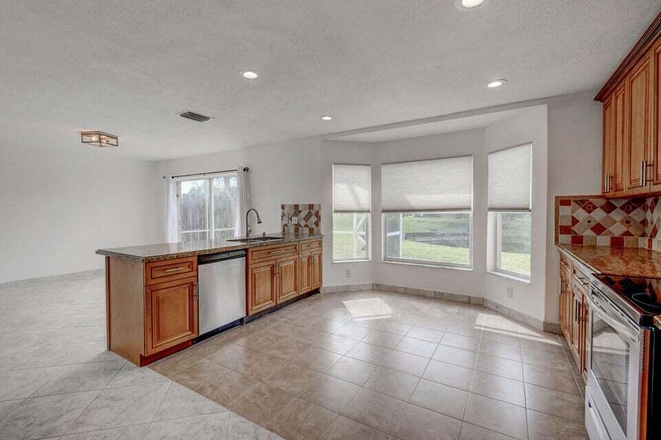 A kitchen with wood cabinets, granite countertops, tile flooring, and a bay window — 10758 Lake Jasmine Drive, Boca Raton FL 33498, BOCA RATON, FL