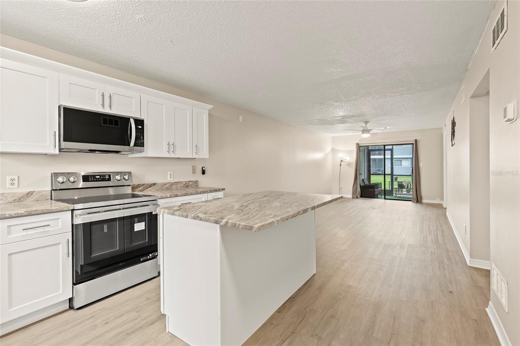 A kitchen features white cabinets, stainless steel appliances, and granite countertops with a central island — 6033 34TH STREET W UNIT 83, BRADENTON, FL