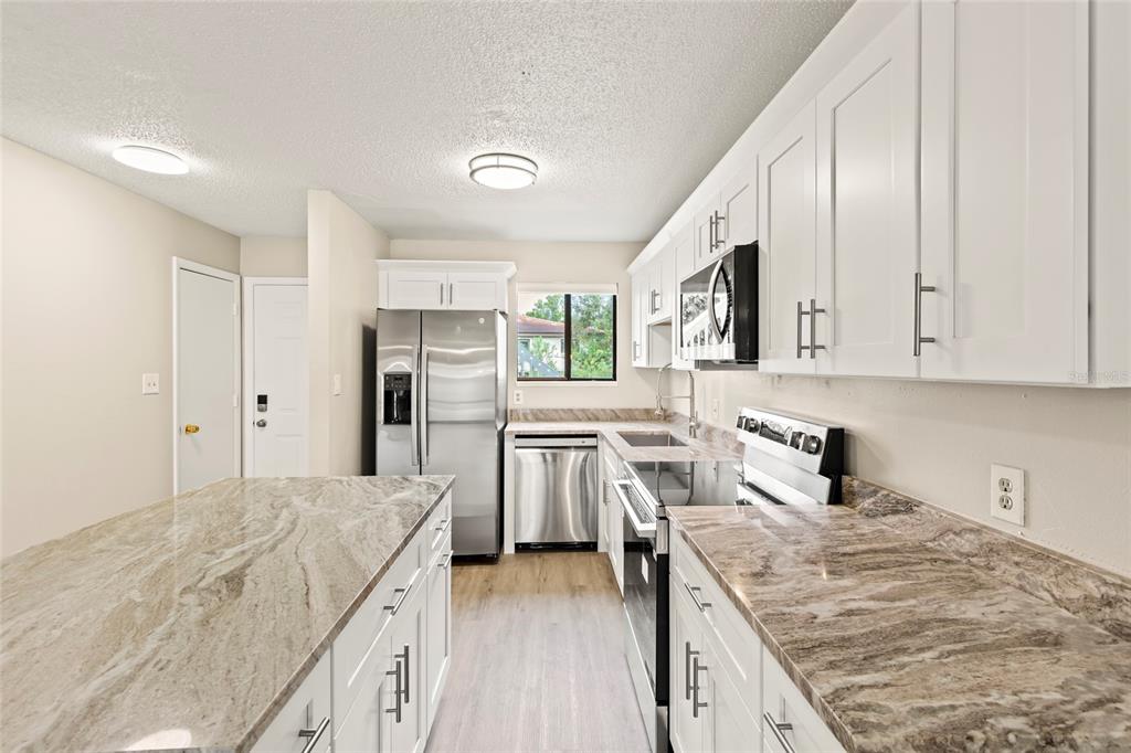 A kitchen features white cabinets, stainless steel appliances, and brown patterned granite countertops — 6033 34TH STREET W UNIT 83, BRADENTON, FL
