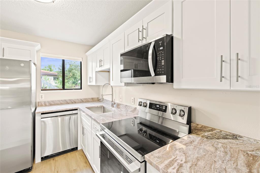 A kitchen features white cabinets, stainless steel appliances, and a granite-topped island — 6033 34TH STREET W UNIT 83, BRADENTON, FL