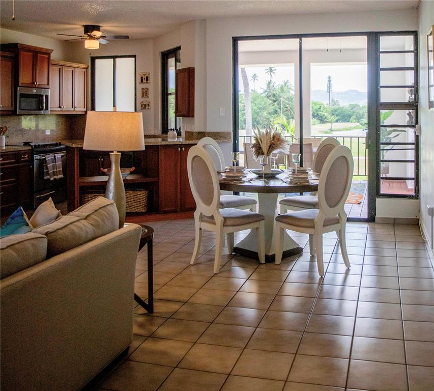 An open-concept living and dining area features tile floors, wooden cabinetry, and a balcony view — 185 CANDELERO DRIVE UNIT 671, HUMACAO, PR
