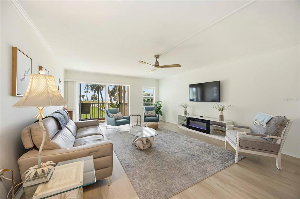 A bright living room features a leather sofa, area rug, and sliding doors to a balcony — 1150 TARPON CENTER DRIVE UNIT 208, VENICE, FL