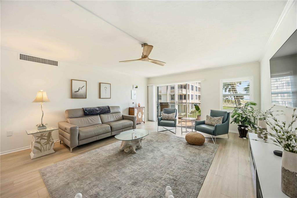 A living room features a gray sofa, two blue armchairs, a rug, and a ceiling fan — 1150 TARPON CENTER DRIVE UNIT 208, VENICE, FL