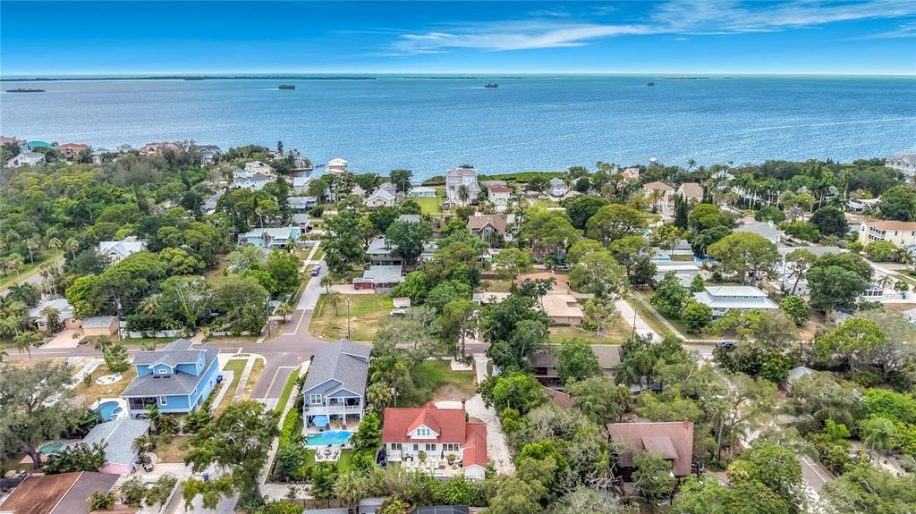 An aerial view shows a coastal neighborhood with houses, lush trees, and the ocean beyond — 675 S VINCENT STREET, CRYSTAL BEACH, FL