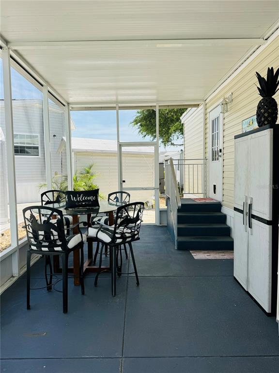A screened-in porch features a dining set, a storage cabinet, and stairs leading to a doorway — 300 ROYAL TROON LOOP, DAVENPORT, FL