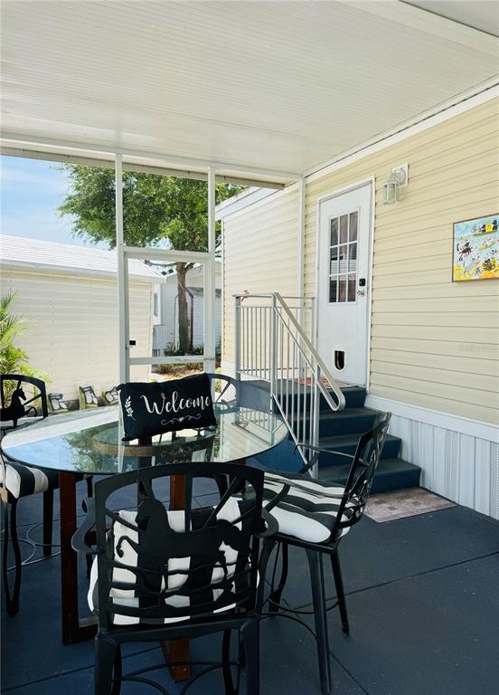 A screened-in porch features a glass-top table, black metal chairs, and stairs leading to a door — 300 ROYAL TROON LOOP, DAVENPORT, FL