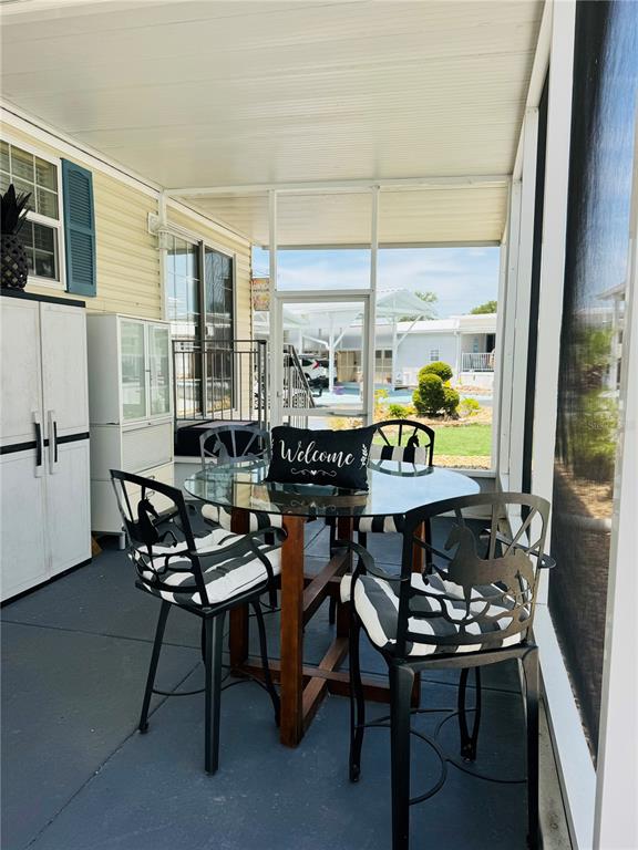 A screened-in patio features a glass-topped dining table with four black metal chairs — 300 ROYAL TROON LOOP, DAVENPORT, FL