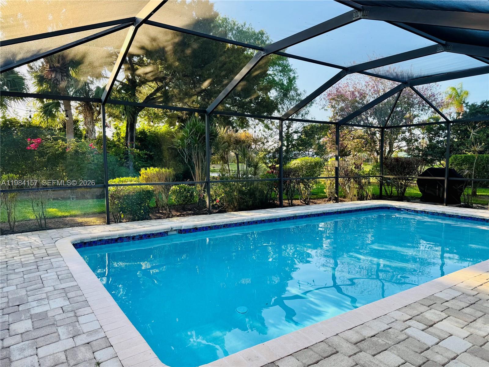 A rectangular swimming pool is enclosed by a screened lanai with paver decking — 3482 SE Court Dr, Stuart FL 34997, STUART, FL