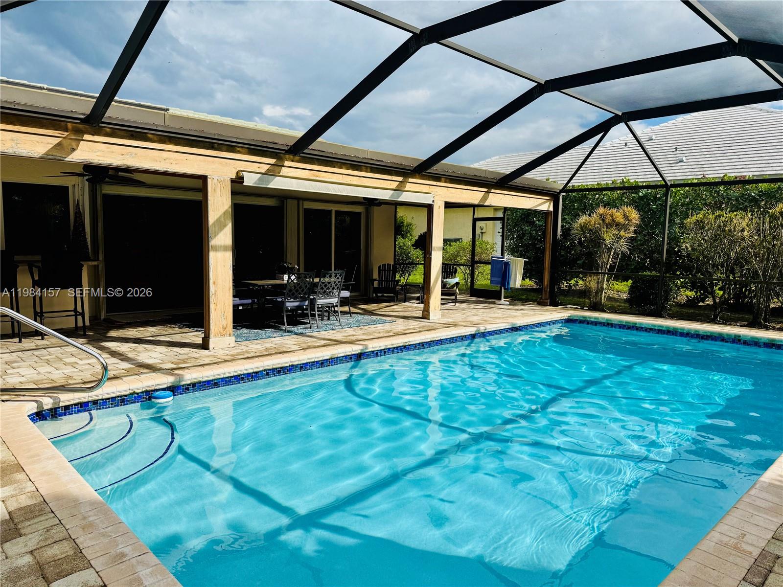 A screened-in patio features a swimming pool with steps and outdoor dining furniture — 3482 SE Court Dr, Stuart FL 34997, STUART, FL