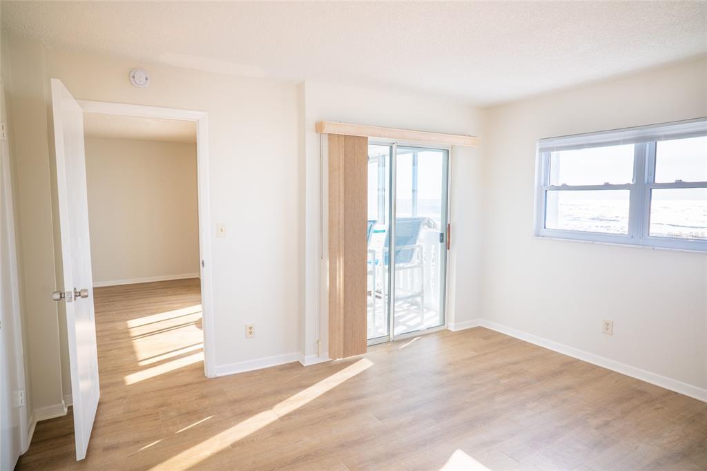 An empty room with light wood flooring, a sliding glass door, and a window view — 403 GULF WAY UNIT 304, ST PETE BEACH, FL