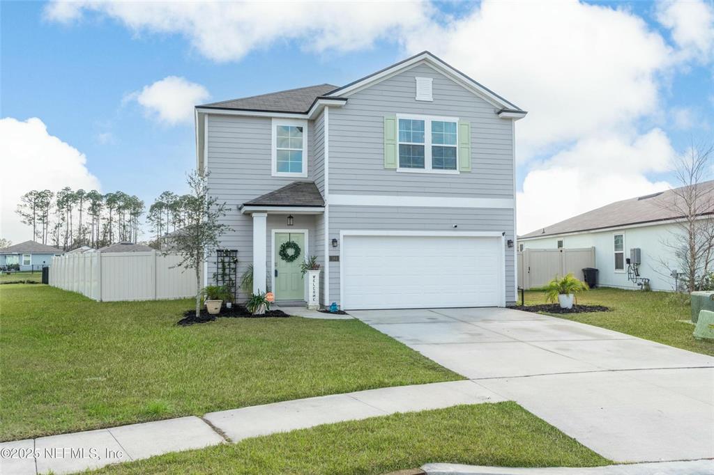 A two-story house with light gray siding, a white garage door, and a green front door — 184 LOGRONO COURT, ST AUGUSTINE, FL