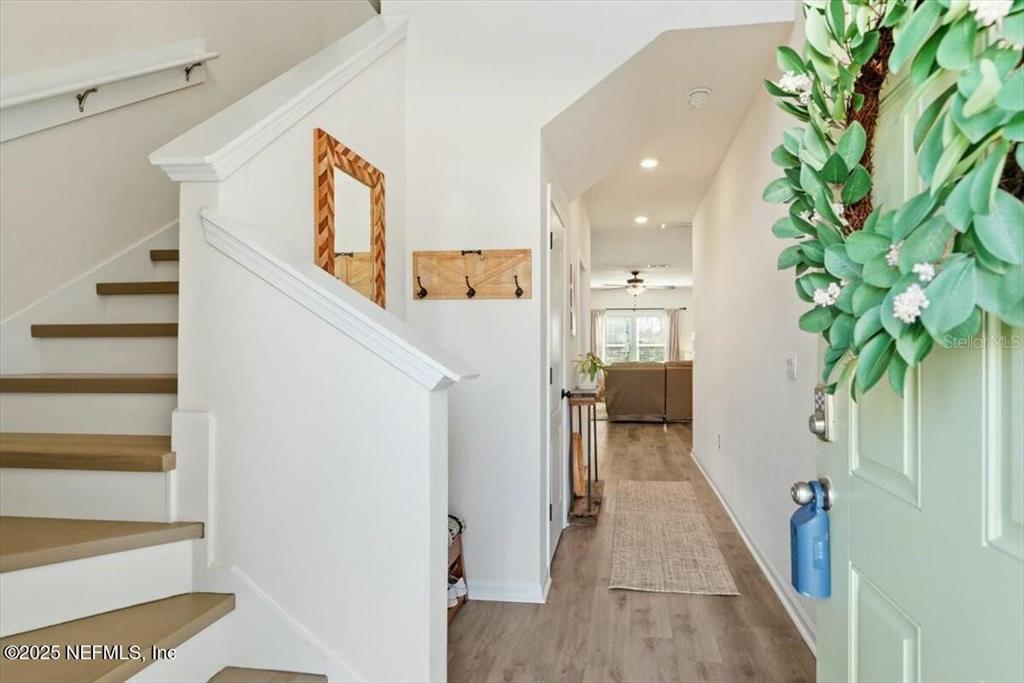 An entryway features a staircase, light wood flooring, a wall-mounted coat rack, and a wreath — 184 LOGRONO COURT, ST AUGUSTINE, FL