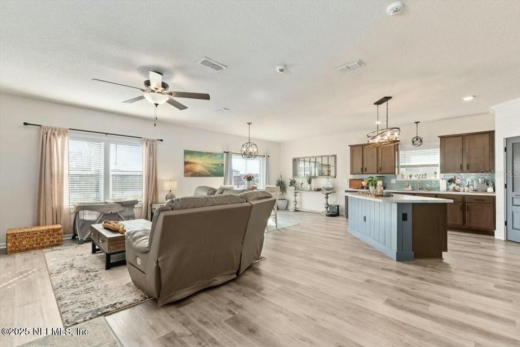 An open-concept living room and kitchen feature light wood flooring and a blue island — 184 LOGRONO COURT, ST AUGUSTINE, FL