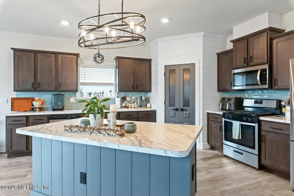 A kitchen features dark wood cabinets, a blue island with a marble countertop, and stainless appliances — 184 LOGRONO COURT, ST AUGUSTINE, FL