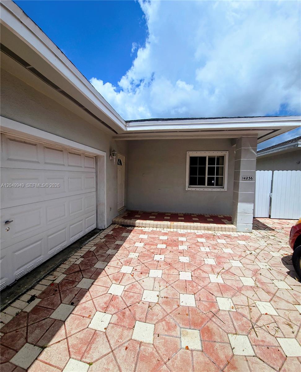 A paved driveway leads to a house entrance with a garage and a white fence — 14236 SW 148th Ave, Miami FL 33196, MIAMI, FL