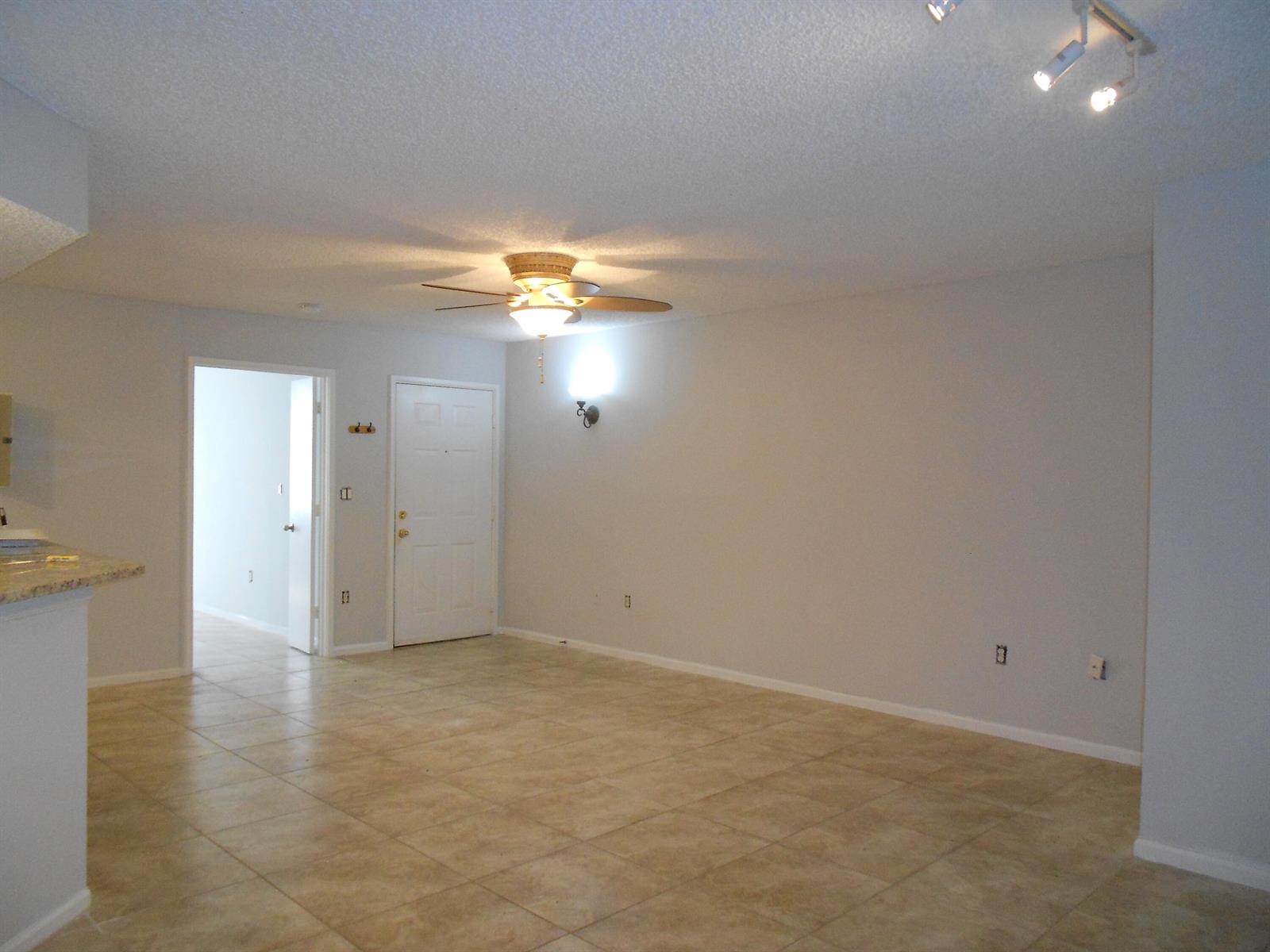An open living area features light-colored tile flooring, a ceiling fan, and a white door — 300 Scotia Drive # 203, Hypoluxo FL 33462, HYPOLUXO, FL