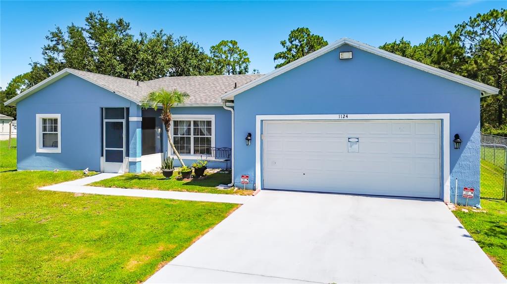 A blue single-story house with a white garage door and a front walkway — 1124 DARTFORD DRIVE, KISSIMMEE, FL