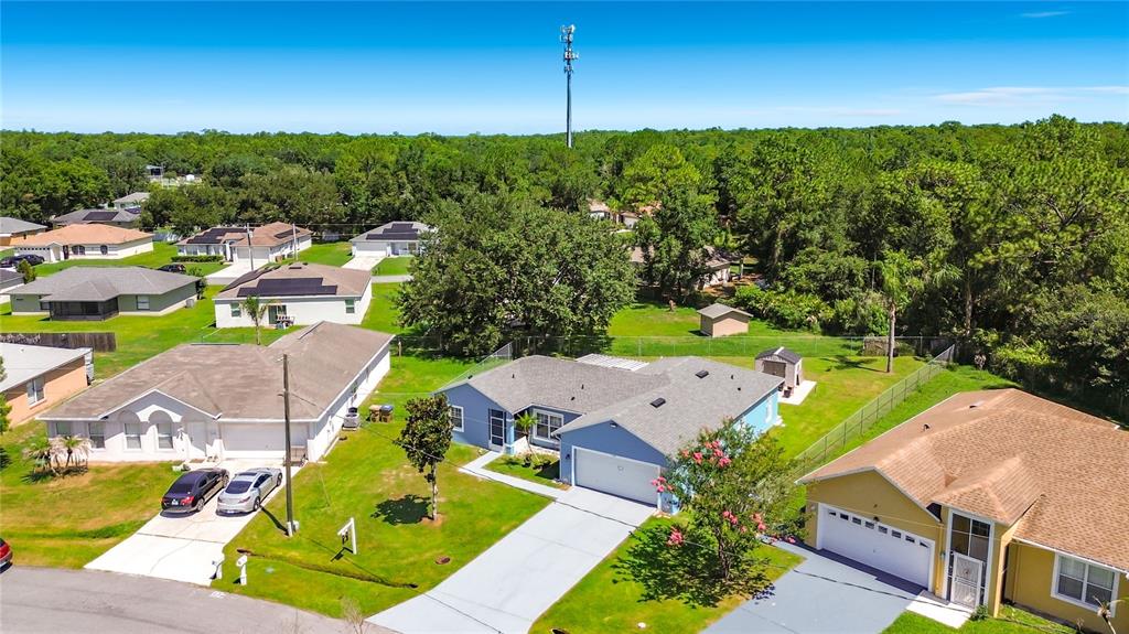 An aerial view shows several suburban houses with driveways and lawns under a clear sky — 1124 DARTFORD DRIVE, KISSIMMEE, FL