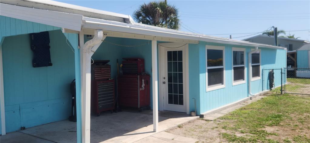 A light blue mobile home exterior features a covered concrete patio with red tool chests — 324 CALLE LIANA, ENGLEWOOD, FL